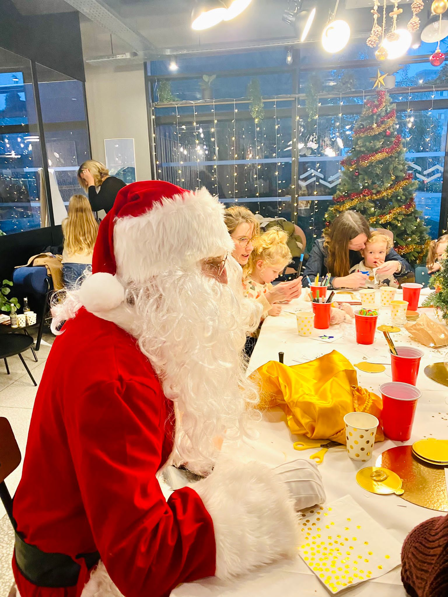 Le Père Noël en visite lors d’un arbre de Noël, entouré d’enfants enthousiastes par My Art Event.